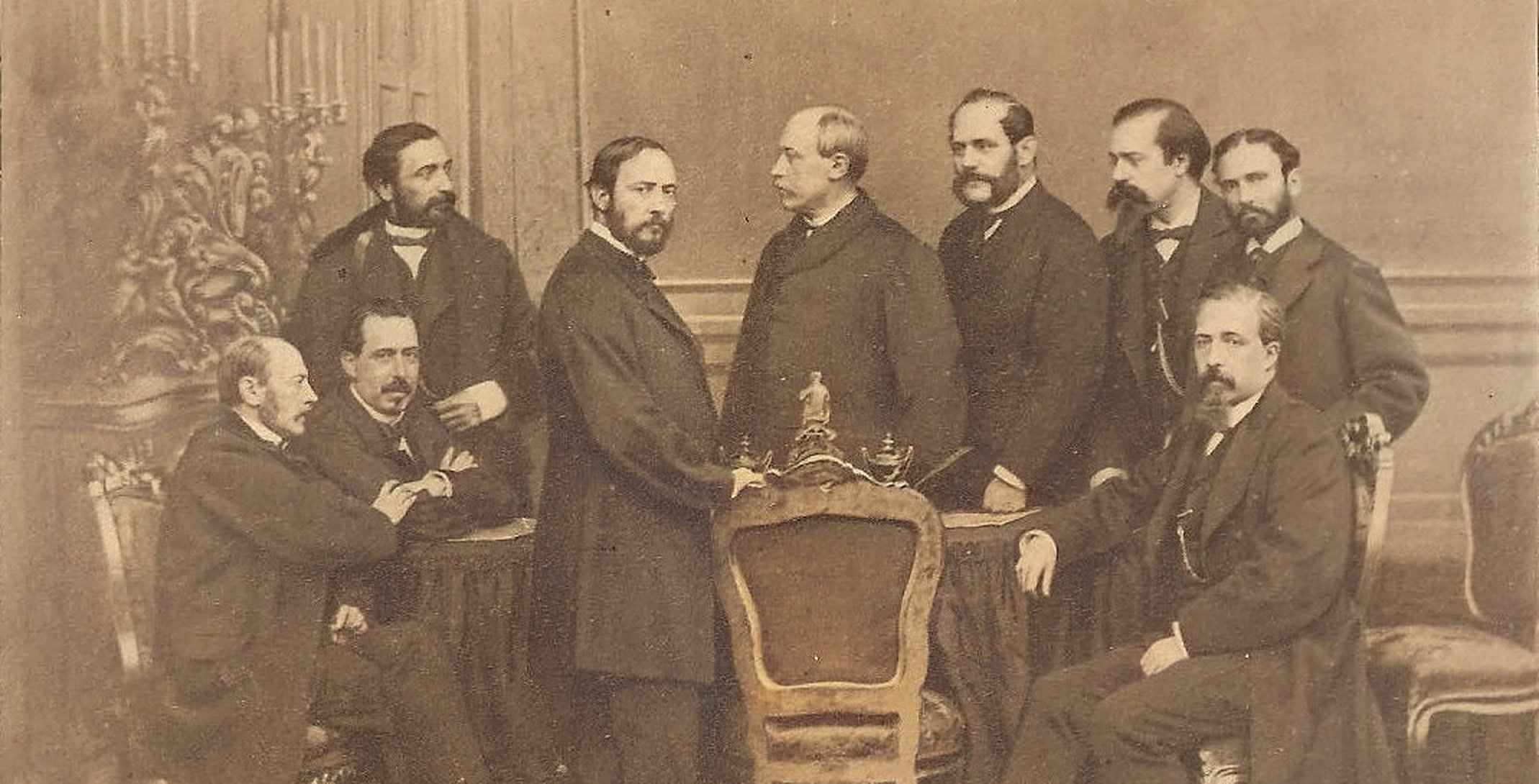 Group portrait of Spain's Provisional Government in 1869, men in dark coats seated and standing around a table.