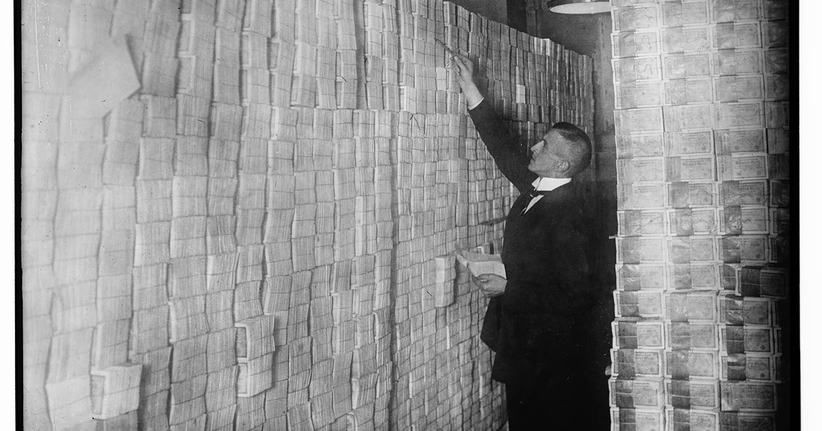 Crowded Berlin bank interior during the German hyperinflation period, customers packed at teller windows.
