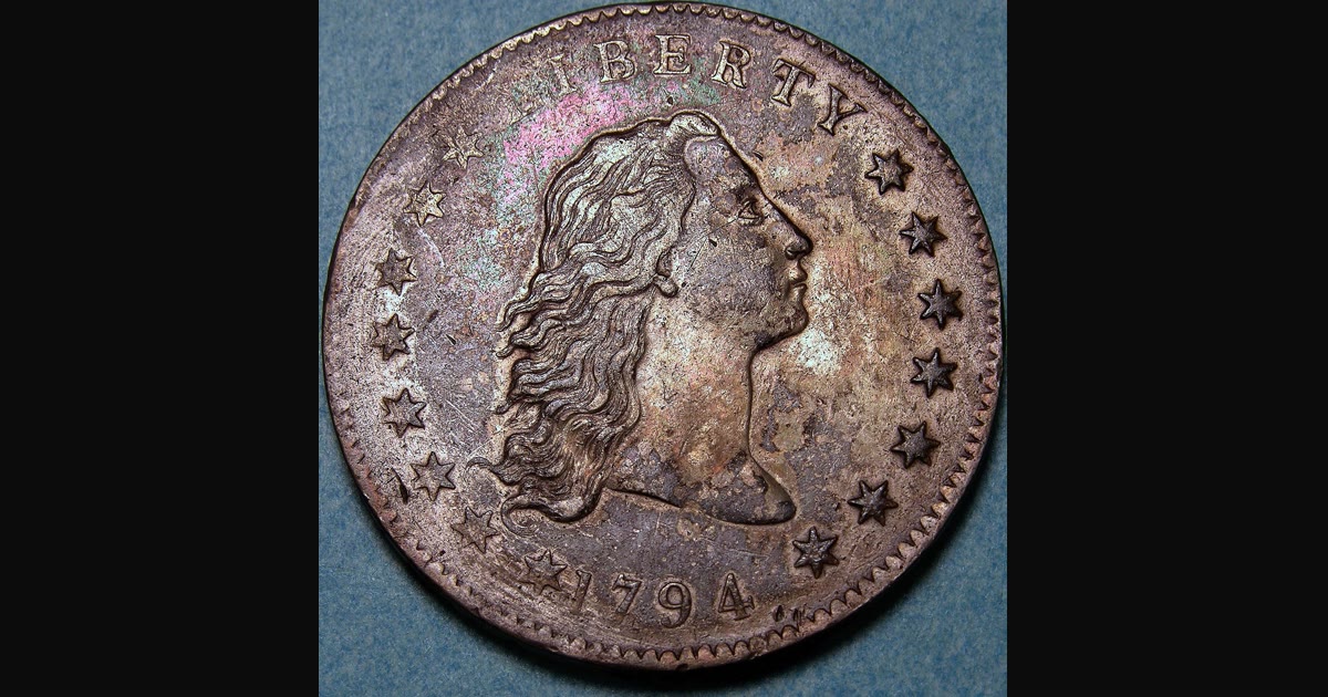 Flowing Hair silver dollar coin on a dark background.